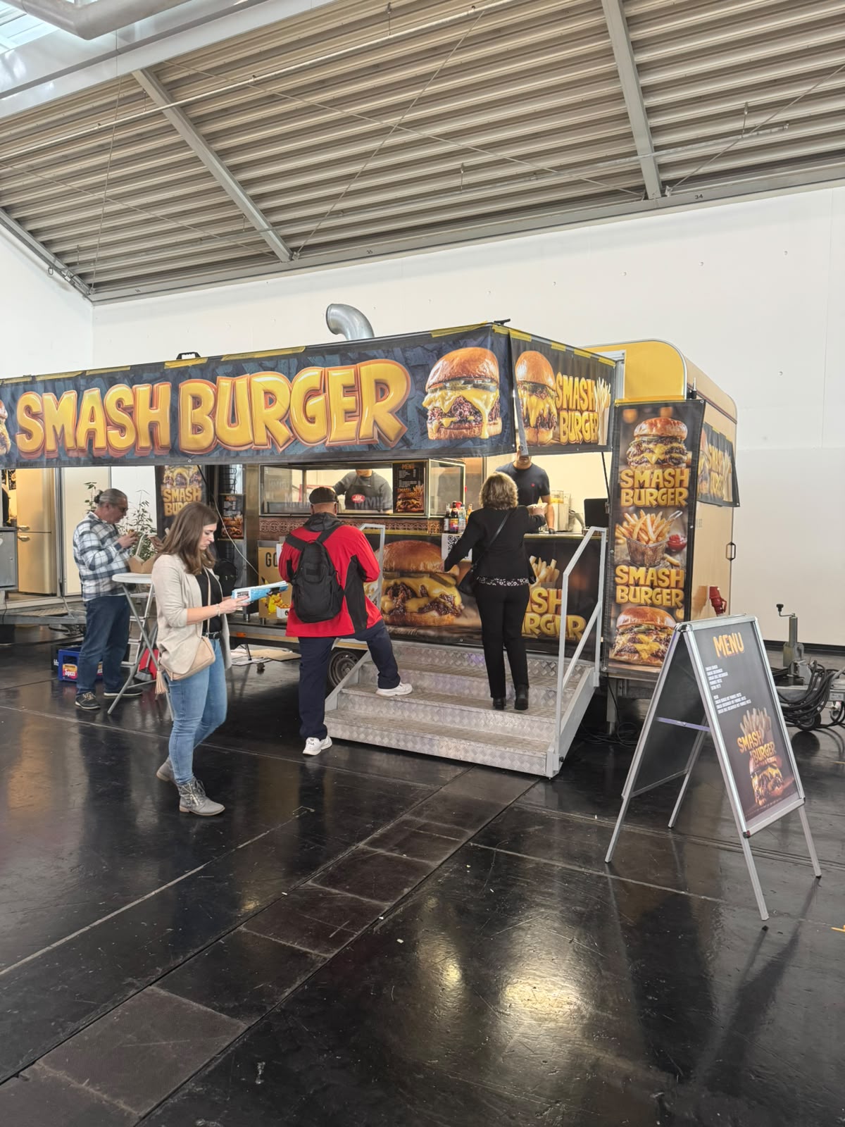 Golden Grill Foodtruck mit Gästen bei einer Veranstaltung in einer Halle